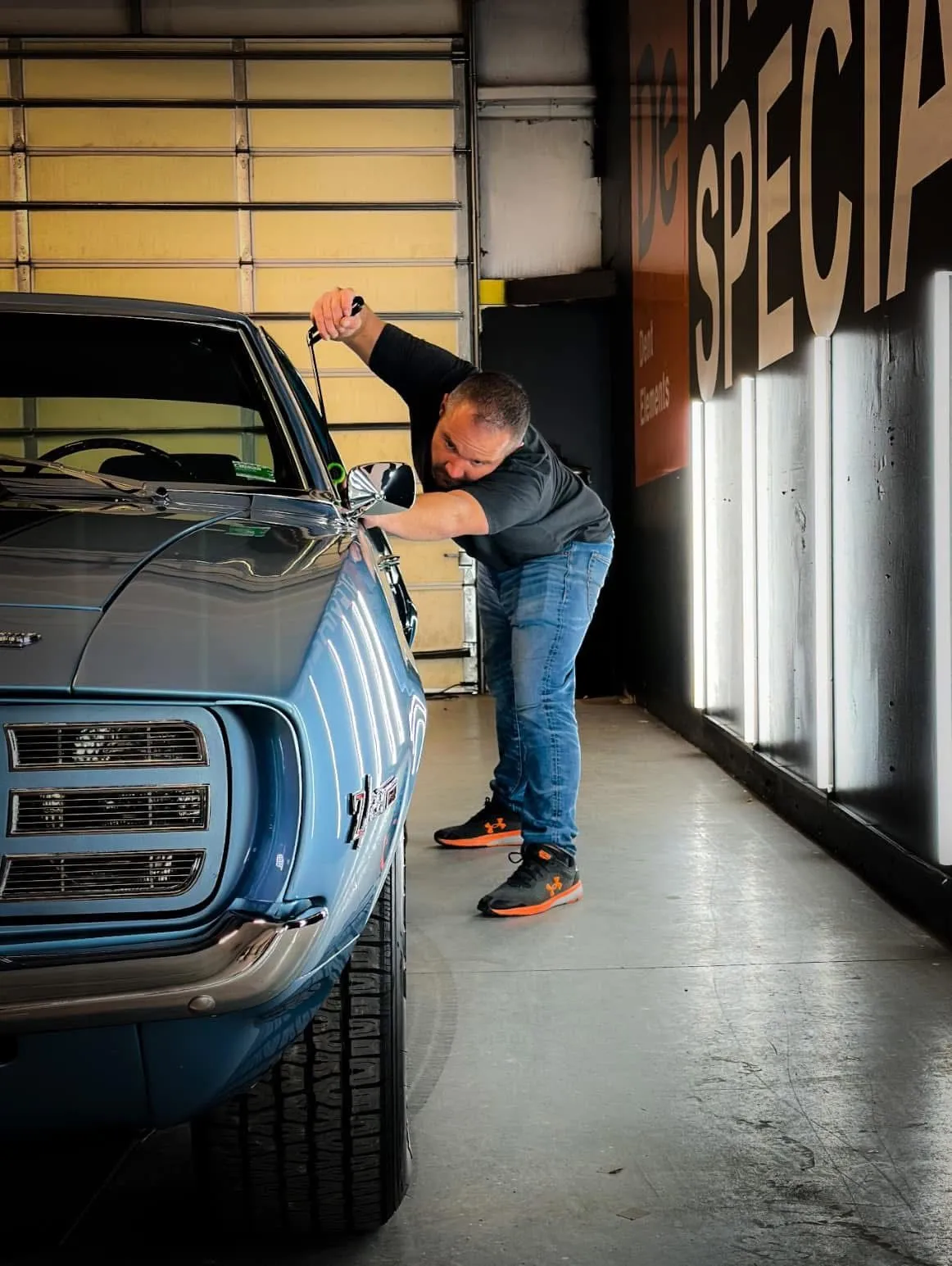 Dent Elements technician repairing a dent on a classic blue Camaro